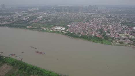 Luftaufnahme-Eines-Gewundenen-Flusses-Und-Einer-Stadt,-Die-An-Seinen-Ufern-Gebaut-Wurde.-Es-Gibt-Auch-Mehrere-Brücken,-Die-Den-Fluss-überqueren,-Darunter-Eine-Rote-Hängebrücke