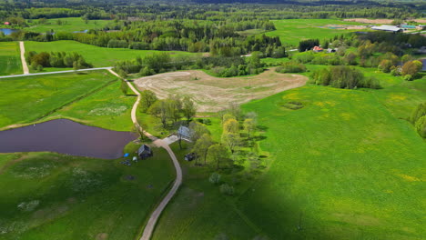 Rural-village-countryside-in-spring-green-atmosphere-aerial-drone-panoramic-shot,-a-path-between-green-meadows