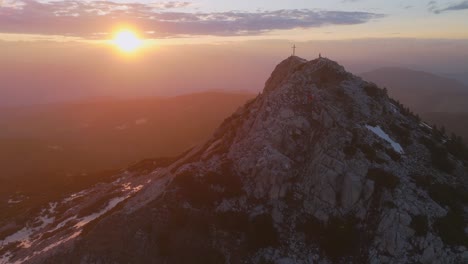 Eine-Atemberaubende-Luftaufnahme-Des-Corno-Bianco-Berg-Bei-Sonnenuntergang-Mit-Einem-Kreuz-Auf-Dem-Gipfel