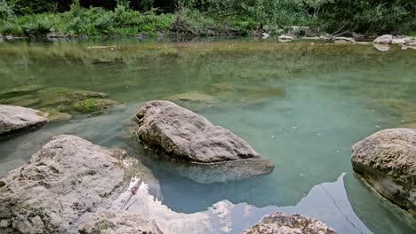 Dieses-Ruhige-Archivmaterial-Zeigt-Einen-Ruhigen-Kleinen-Fluss-Mit-Langsamer-Strömung,-Umgeben-Von-üppigem-Grün