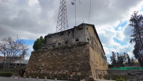 Una-Fortificación-Histórica-En-Nicosia,-Chipre,-Con-Un-Antiguo-Muro-De-Piedra-Y-Una-Moderna-Torre-De-Comunicaciones,-Capturada-En-Cámara-Lenta