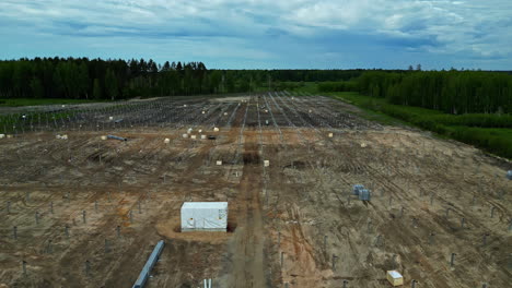 Drone-Aéreo-Vuela-Sobre-El-Paisaje-Rural-Industrial-De-La-Granja-Solar-Con-Fondo-De-Bosque-De-Pinos