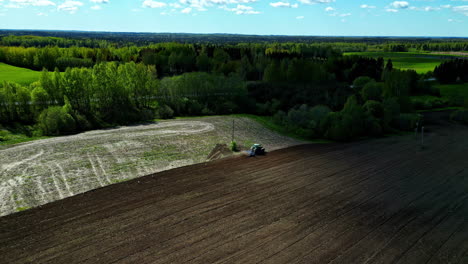Luftaufnahme-Einer-Ländlichen-Landschaft-Mit-Einem-LKW,-Der-Auf-Landwirtschaftlichen-Feldern-Arbeitet,-Boden,-Grüner-Wald,-Skyline-Hintergrund