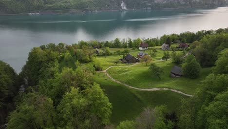 Aerial-view-of-a-flat-plateau-with-houses-overlooking-Lake-Walensee,-Switzerland,-embodying-a-serene-blend-of-residential-tranquility-and-breathtaking-natural-beauty