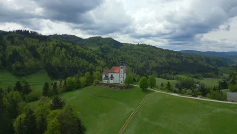 Tranquil-green-valley,-moody-cloudy-sky,-gothic-church-architecture