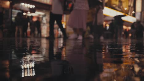 Llueve-A-Cántaros-En-La-Calle-Por-La-Noche-Con-Gente-Caminando-En-El-Fondo-En-Osaka,-Japón
