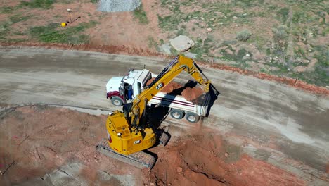 Track-hoe-loading-dump-truck-with-red-soil