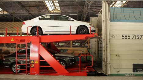 Cars-being-loaded-onto-a-two-level-car-transport-train-under-a-large-shed