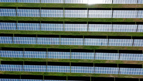 Paneles-Solares-Alineados-Sobre-Hierba-Verde,-Mostrando-Energía-Renovable,-Vista-Aérea
