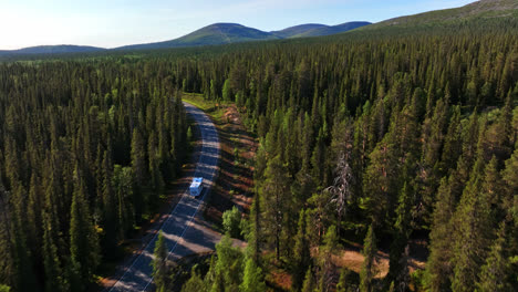 AERIAL:-Motor-home-driving-toward-mountains-in-the-arctic-nature-of-sunny-Lapland
