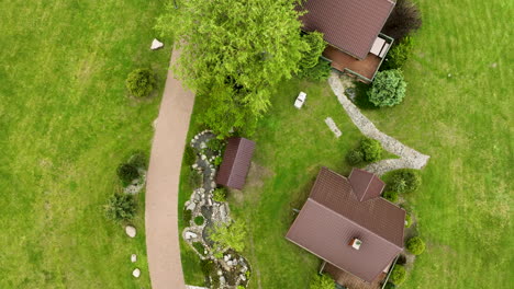 Eine-Luftaufnahme-Von-Oben-Eines-Grundstücks-Mit-Einem-Haus,-Wegen-Und-Einem-Kleinen-Gartenbereich,-Umgeben-Von-Grünen-Rasenflächen