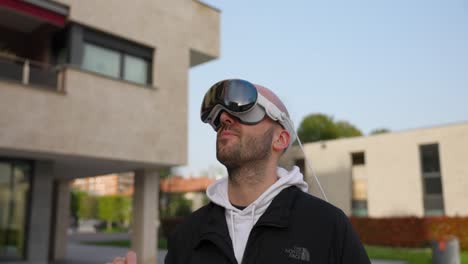 Close-up-of-man-using-a-virtual-reality-headset-outdoors-while-gesturing-and-speaking