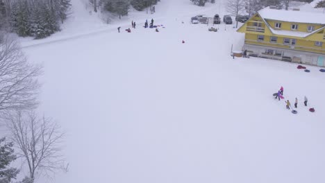 Drone-shot-of-people-sledding-down-hill-on-small-hill-in-Estonia