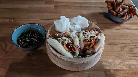 Bollos-Bao-Al-Vapor-Con-Verduras-Encurtidas-Y-Salsa-Sobre-Una-Mesa-De-Madera