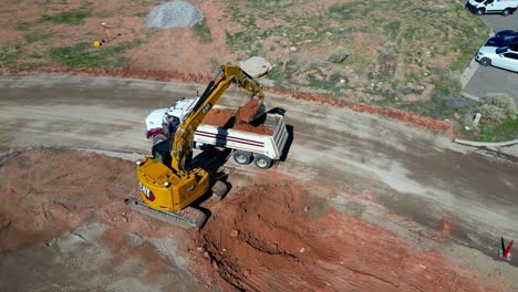 Excavator-fills-dump-truck-with-red-soil