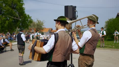 Annual-traditional-Bavarian-May-festival-celebration-with-musicians,-people,-maypole,-whips,-leather-pants