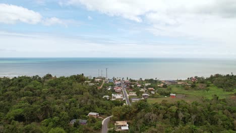 Drone-flying-over-small-village-towards-the-ocean