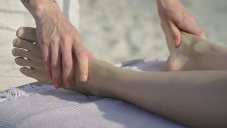 Hände-Massieren-Den-Fuß-Einer-Person-Auf-Einem-Strandtisch-In-Einer-Beruhigenden-Umgebung-Im-Freien