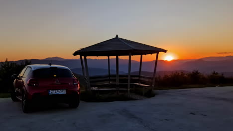 Sunset-view-over-mountains,-car-and-gazebo-in-foreground,-majestic-landscape