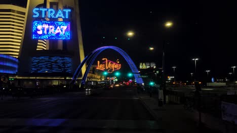 Fahren-Auf-Dem-Las-Vegas-Strip-Bei-Nacht,-Wahrzeichen-Bogen-Zeichen,-Strat-Casino-Hotel,-Straßenampeln