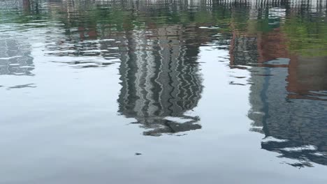 Rippling-reflections-of-urban-buildings-on-calm-water-on-a-clear-day