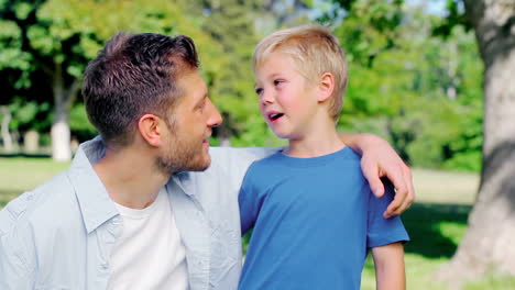 Boy-having-a-discussion-with-his-father-as-they-embrace-in-a-park