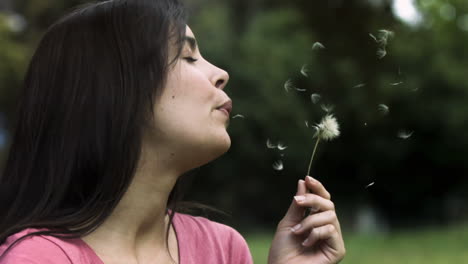 Woman-blowing-a-dandelion-in-slow-motion