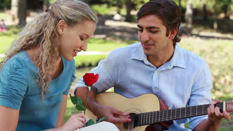 A-man-serenades-his-girlfriend-with-a-song-as-she-holds-a-rose-as-they-look-at-the-camera