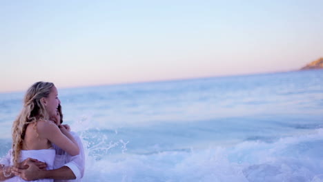 Couple-on-the-beach-running-while-kissing-after-getting-hit-by-a-wave