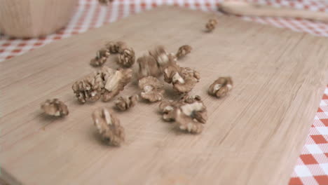 Walnut-kernels-falling-in-super-slow-motion-on-a-wood-board