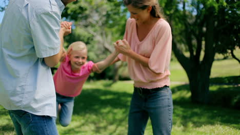 Girl-being-swung-back-and-forth-by-his-parents-who-are-holding-her-arms
