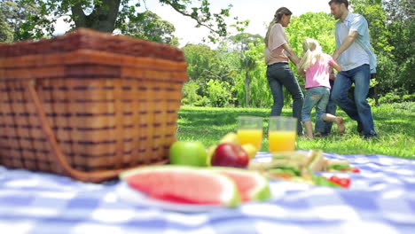 Family-dancing-in-a-cirlcle-in-the-background-with-a-platter-on-a-picnic-basket-in-the-foreground