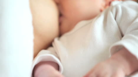 Woman-holding-babys-hands-while-she-breastfeeds
