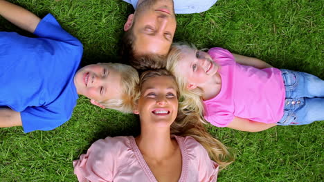 Overhead-shot-of-a-family-smiling-as-they-lie-head-to-head-in-grass
