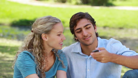 Woman-with-a-phone-passing-it-to-her-boyfriend-who-talks-and-then-hangs-up-as-they-look-forward