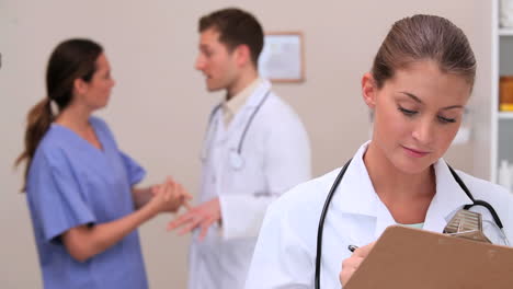 Smiling-doctor-writing-on-her-clipboard