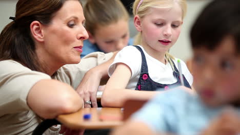 Happy-teacher-helping-a-blonde-pupil