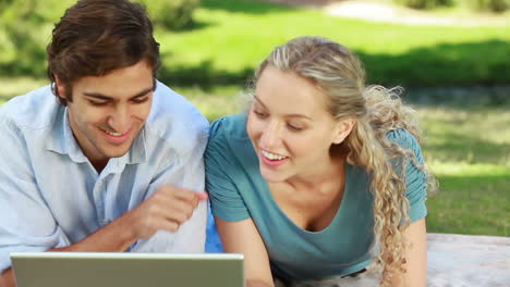Woman-lies-down-beside-her-boyfriend-as-they-watch-a-laptop-and-then-look-into-the-camera
