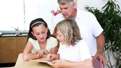 Children-using-a-tablet-computer-in-front-of-their-father