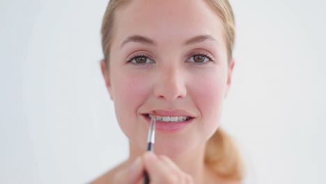 Smiling-woman-using-a-lip-brush