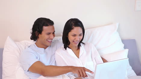 Couple-in-a-bed-using-a-laptop