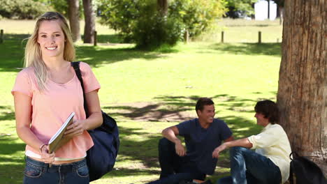 Woman-waving-towards-her-friends-who-are-sitting-behind-her-before-she-looks-at-the-camera