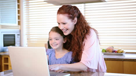 Smiling-mother-and-daughter-using-a-laptop