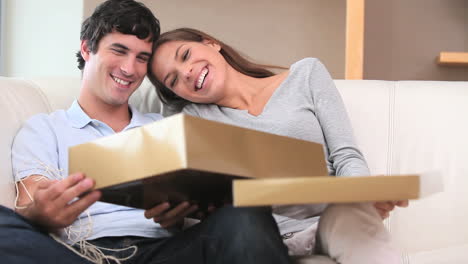 Brunette-woman-opening-a-gift-with-her-boyfriend