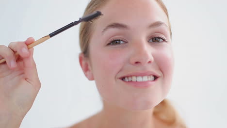 Smiling-blonde-woman-brushing-her-eyebrows