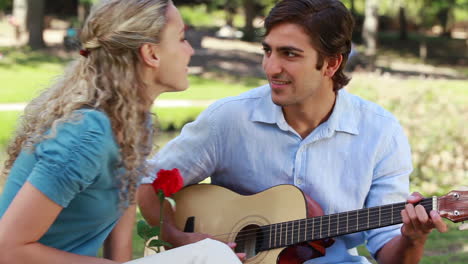 Freund-Spielt-Gitarre-Für-Seine-Freundin,-Während-Sie-Eine-Rose-Hält-Und-Dann-Küsst