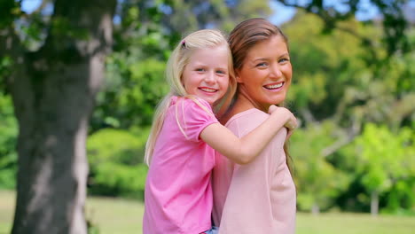 Woman-lifts-her-daughter-into-a-piggyback-before-smiling