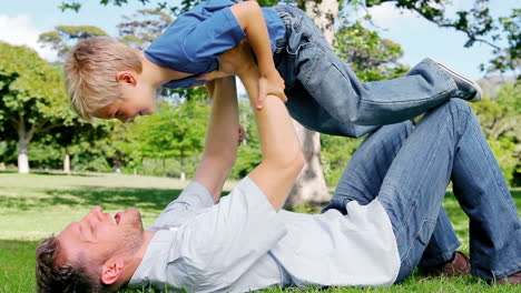 Father-lies-on-the-grass-and-raises-his-son-in-the-air-as-he-pretends-to-be-and-airplane