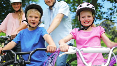 Family-enjoys-a-bike-ride-in-the-park,-waving-and-smiling.