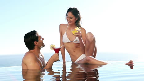 Couple-in-a-swimming-pool-drinking-cocktails